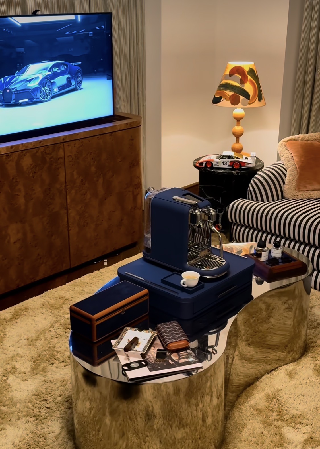 The Scrigno Chest in Marine navy leather, resting on a chrome coffee table in a luxury living room