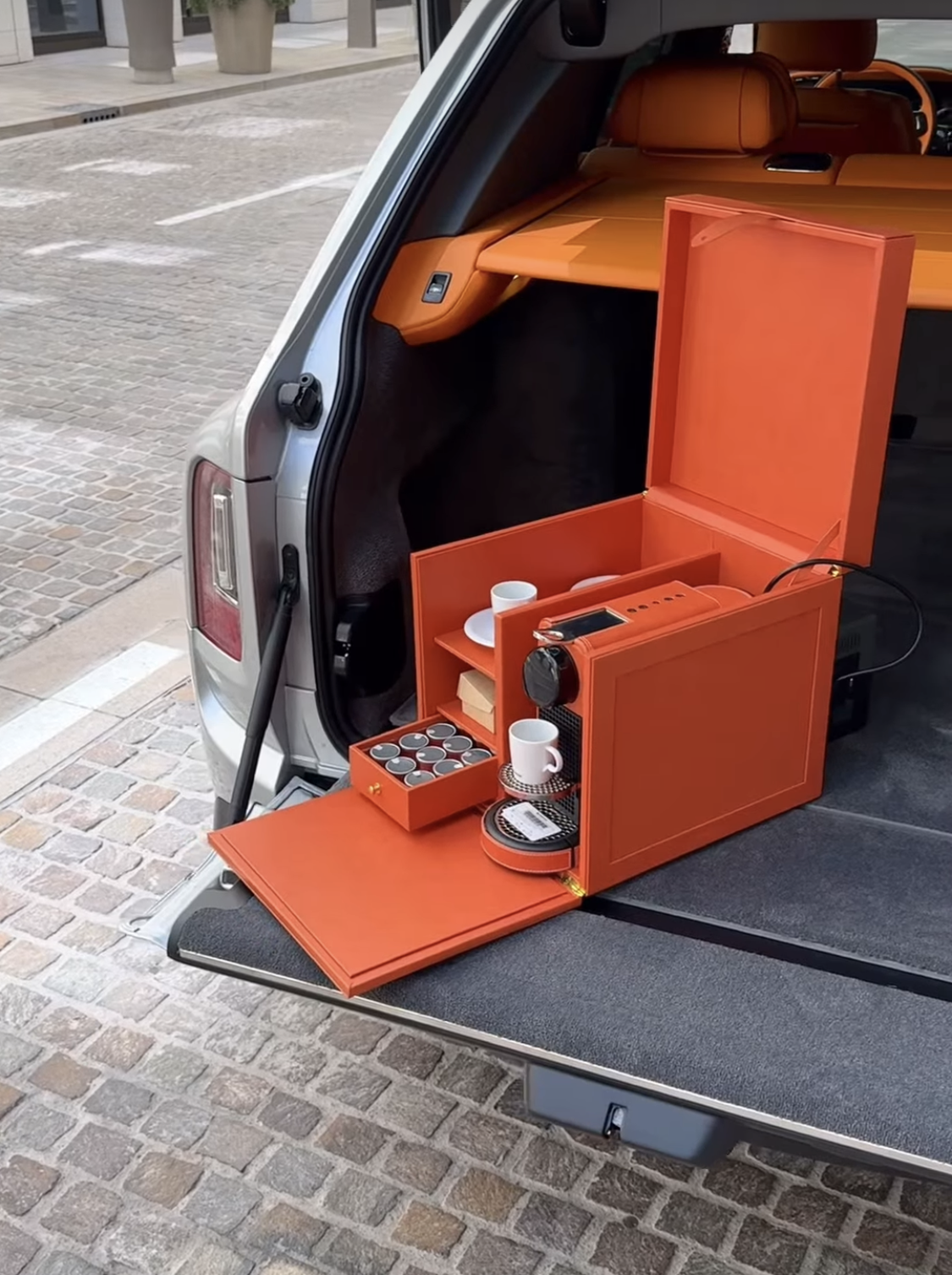 The Scrigno Chest in Cognac orange leather, set in the boot of a Rolls-Royce